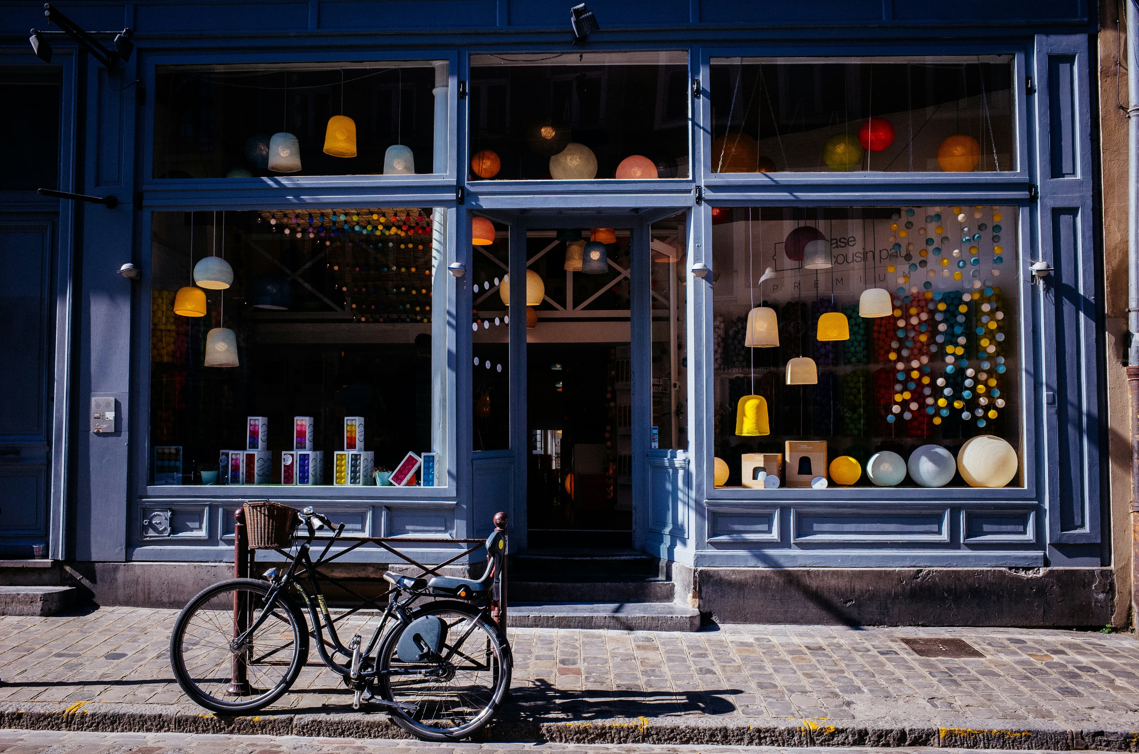 Cykel parkeret på et brostensfortov foran en butiksfacade